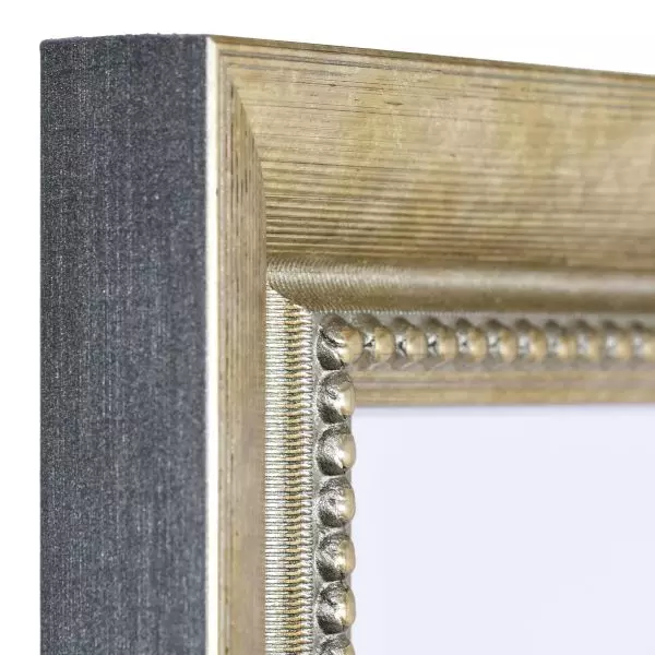 Ansicht der Ecke eines goldenen Bilderrahmens mit einer durch ein Prägerad aufgebrachten Oberfläche und einem Perlstab